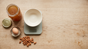 Overhead flat-lay of gelled bone broth jar beside a kitchen scale, egg, and almonds showing protein comparison